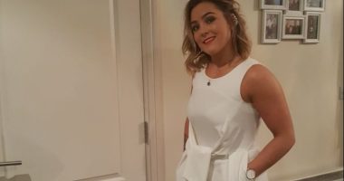 Woman in white jumpsuit and gold heels.