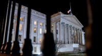 The front facade of the US Treasury building is pictured lit up at night
