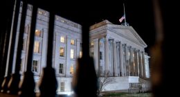 The front facade of the US Treasury building is pictured lit up at night