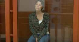 Ksenia Karelina sitting in a courtroom cage.
