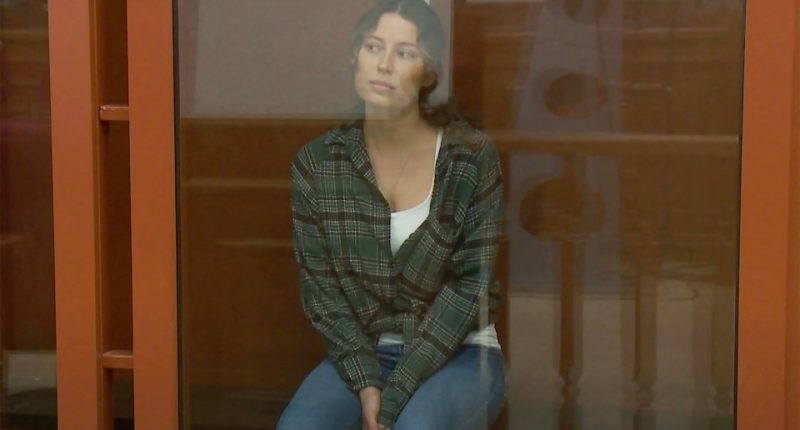 Ksenia Karelina sitting in a courtroom cage.