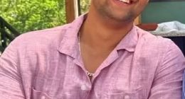 Man in pink shirt holding a cocktail.