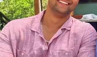 Man in pink shirt holding a cocktail.