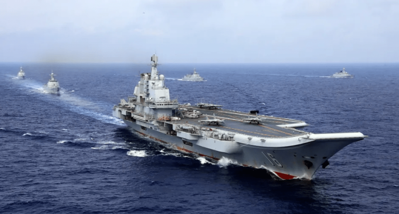 Aircraft carrier and accompanying ships at sea.
