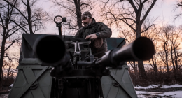 Man operating a military vehicle's anti-aircraft gun.