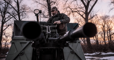 Man operating a military vehicle's anti-aircraft gun.
