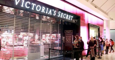 Shoppers wearing masks line up outside a Victoria's Secret store.