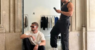 Two men in sunglasses and casual attire sitting outside a store.