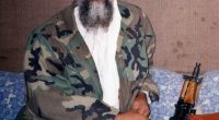 Osama bin Laden sitting with an AK-47.