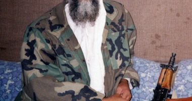 Osama bin Laden sitting with an AK-47.