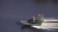 Airboat on water with two people on board.