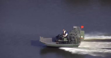 Airboat on water with two people on board.