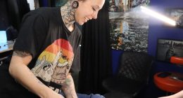 A photo of Kat Farris, a tattoo artist from Enova Ink and Body Art, showing a client a tattoo sketch to cover a self-harm tattoo.