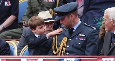 Prince Louis was quick to help out his father Prince William as he brushed down the future King's military uniform at the VE Day celebration at Buckingham Palace today