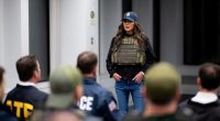 Secretary Kristi Noem in ICE vest briefing law enforcement.
