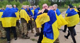 Ukrainian prisoners of war wrapped in Ukrainian flags after a prisoner exchange.