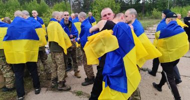 Ukrainian prisoners of war wrapped in Ukrainian flags after a prisoner exchange.