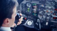 Pilot using a radio in a cockpit.