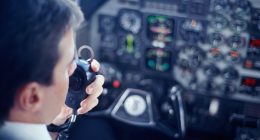 Pilot using a radio in a cockpit.