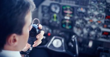 Pilot using a radio in a cockpit.