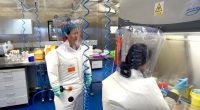 Two scientists in protective suits working in a laboratory.