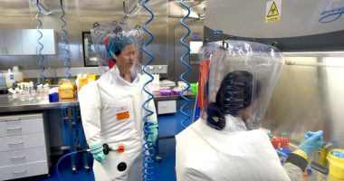 Two scientists in protective suits working in a laboratory.