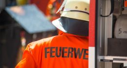 Back of a German firefighter's orange jacket with "FEUERWEHR" printed on it.