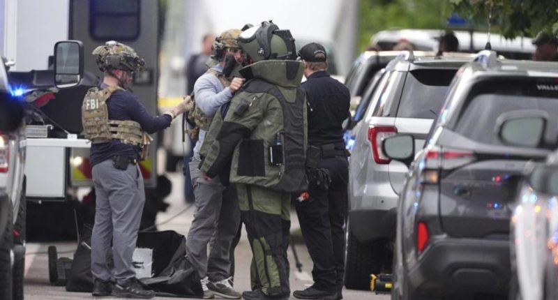 Law enforcement officials dress up in protective gear to investigative an attack on the Pearl Street Mall, Sunday, June 1, 2025, in Boulder, Colo. (AP Photo/David Zalubowski)