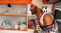 A man, with bandages on his head and shoulder, sits inside an ambulance