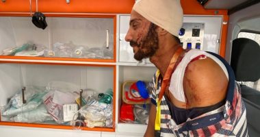A man, with bandages on his head and shoulder, sits inside an ambulance