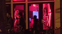 Sex workers are seen behind windows at the red light district in Amsterdam, Netherlands, 24 April 2015. The city's red light district is located in a network of alleys containing approximately three hundred one-room cabins rented by prostitutes who offer their sexual services from behind a window or glass door, typically illuminated with red lights. Amsterdam is one of the most popular tourist destinations in Europe, receiving more than 4.63 million international visitors annually. (Photo by Horacio Villalobos/Corbis via Getty Images)