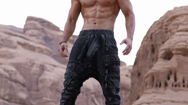 Muscular man standing on a rock.