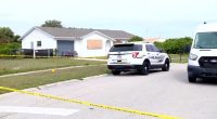 Crime scene at a house with police vehicles.