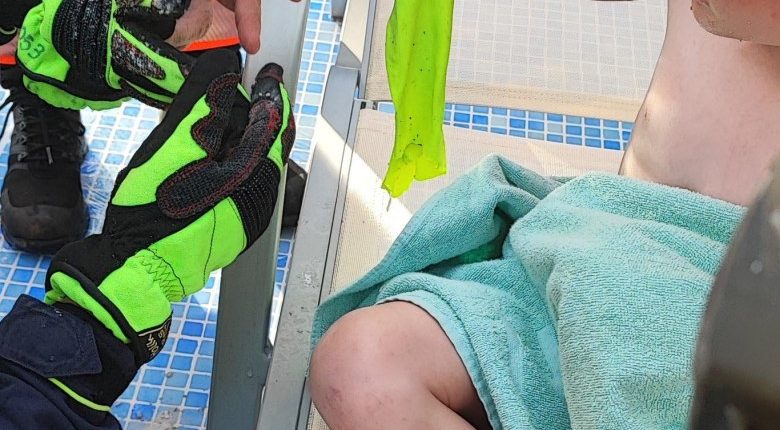 A young boy's arm caught in a pool filter, being rescued.