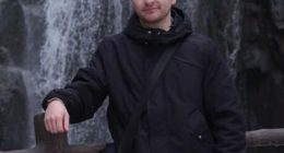 Man standing by a waterfall.