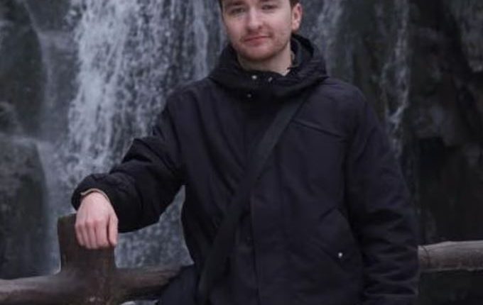 Man standing by a waterfall.