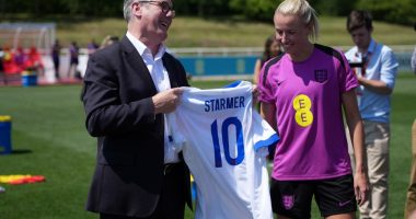 Keir Starmer presents an England football jersey to a member of the Lionesses.