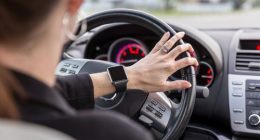 Woman driving a car view from inside of the car and using a smart watch.
