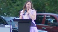 Woman crying while speaking at a podium.