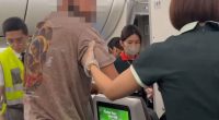 Flight crew removing a passenger from a plane.