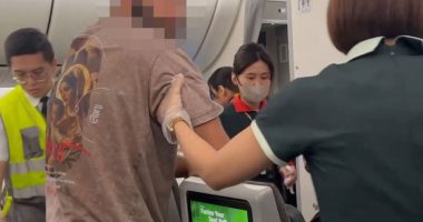 Flight crew removing a passenger from a plane.