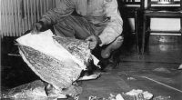 Black and white photo of Jesse Marcel examining debris from a crashed weather balloon in Roswell, New Mexico.