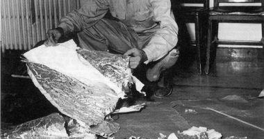 Black and white photo of Jesse Marcel examining debris from a crashed weather balloon in Roswell, New Mexico.