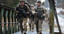 US Army paratroopers crossing a bridge.