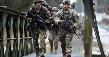 US Army paratroopers crossing a bridge.