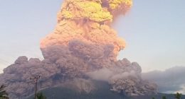 Volcanic eruption plume over a landscape.