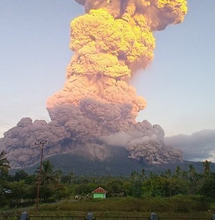 Volcanic eruption plume over a landscape.