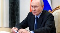 Vladimir Putin reviewing documents at a meeting.