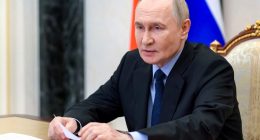 Vladimir Putin reviewing documents at a meeting.