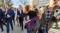 Chrystina Page, right, holds back Heather De Wolf, as she yells at Jon Hallford, left, the owner of Back to Nature Funeral Home, as he leaves with his lawyers following a preliminary hearing, Thursday, Feb. 8, 2024, outside the El Paso County Judicial Building in Colorado Springs, Colo